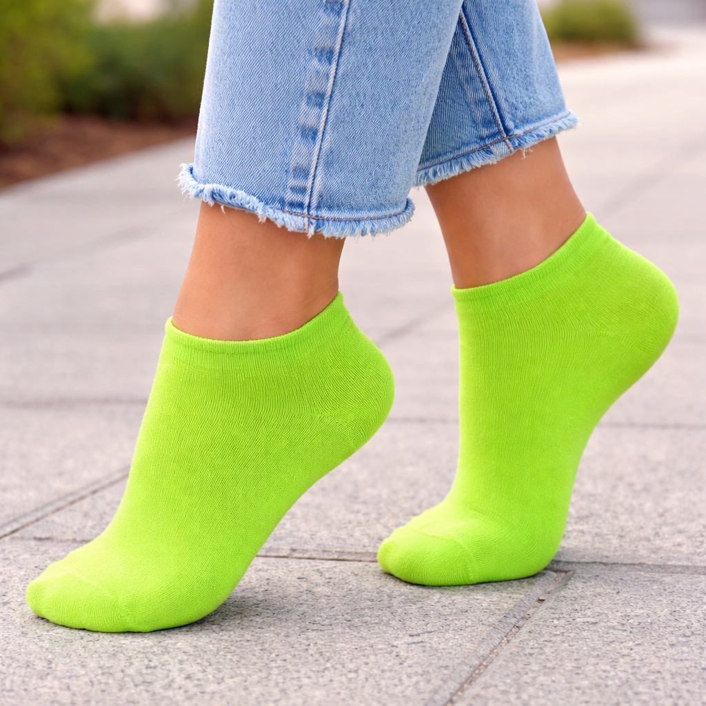 Person wearing bright green Ankle socks and blue jeans on a pavement.
