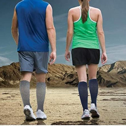 Two people walking on a beach wearing compression socks.