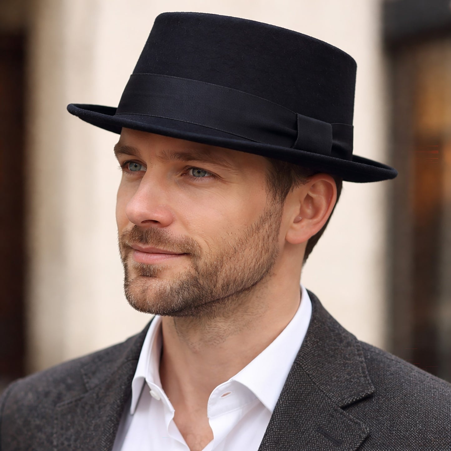 Man wearing a black fedora hat and gray suit with a blurred background